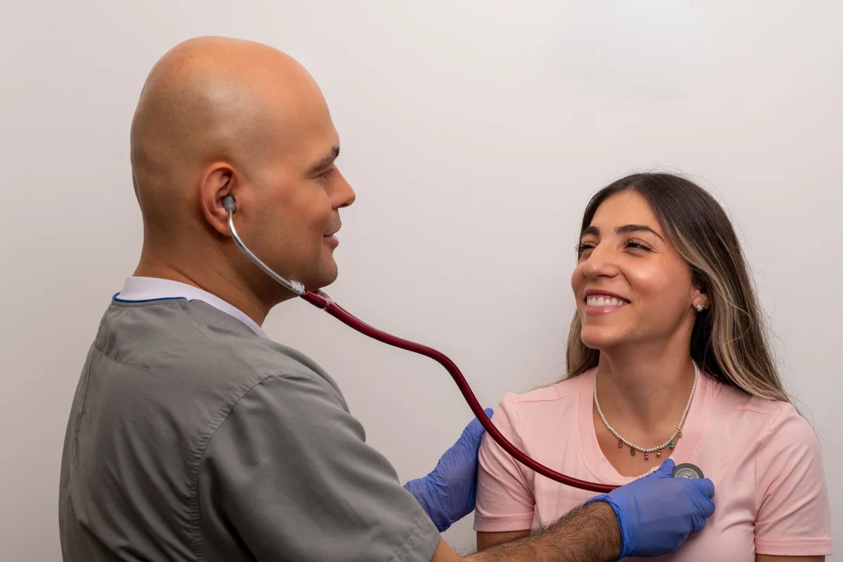 Dr. Daniel Amaya auscultando los campos pulmonares con estetoscopio durante consulta de asma y alergias