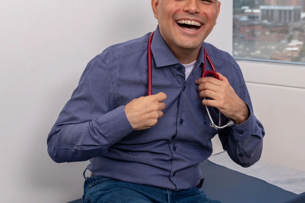 Dr. Daniel Amaya sonriendo en su consultorio médico con vista a Medellín con motivo del Día Mundial de la Alergia