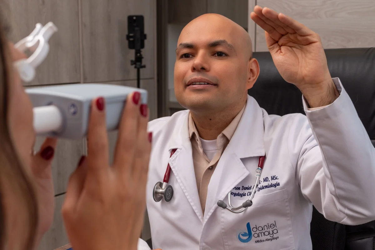 Dr. Daniel Amaya conversando con una paciente que sostiene un dispositivo de medición del flujo respiratorio