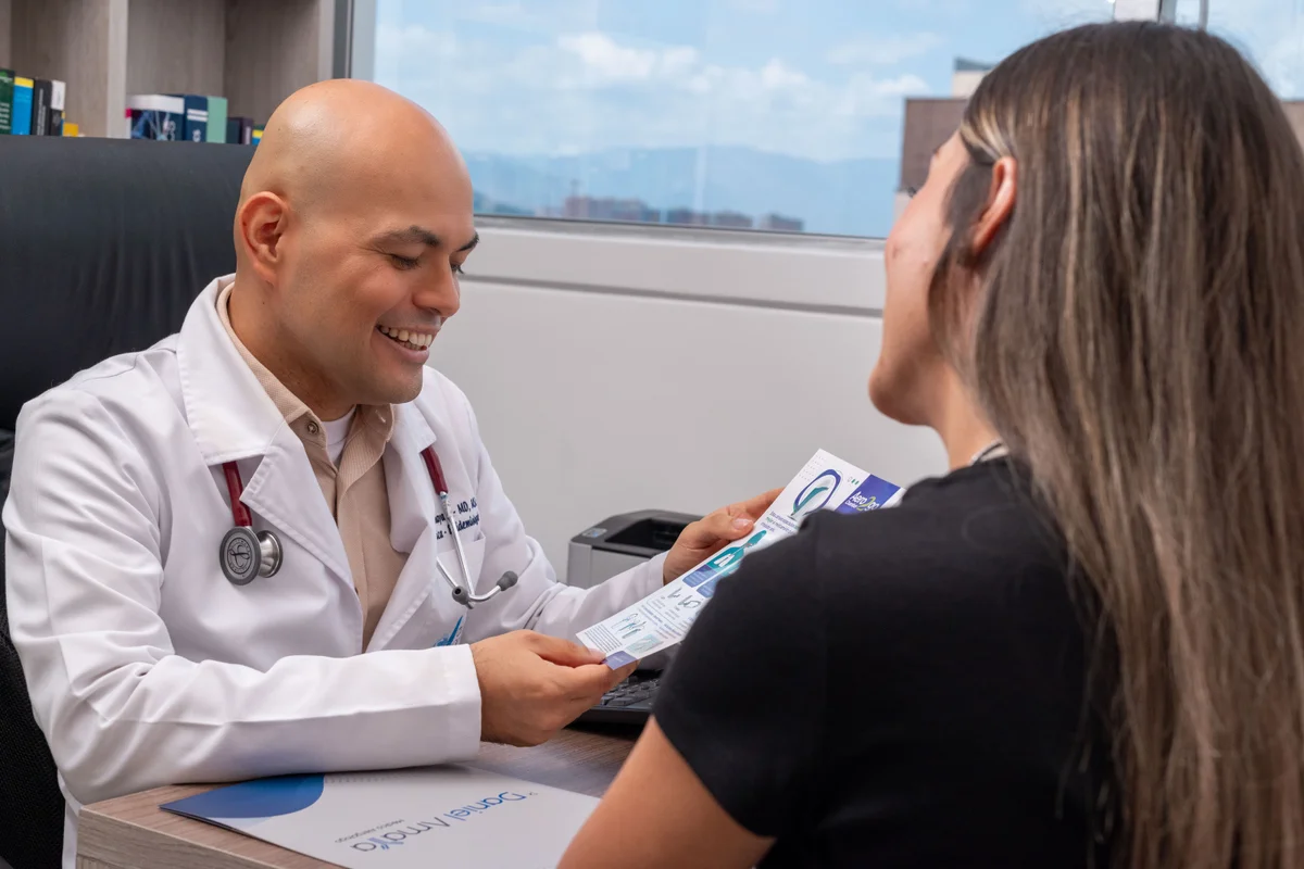 Dr. Daniel Amaya entregando a una paciente material educativo sobre la técnica correcta del inhalador